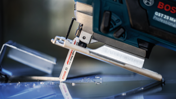 จิ๊กซอว์ตัดแผ่นกระจกที่มีเศษกระจกกระจัดกระจายอยู่ใกล้ๆ.