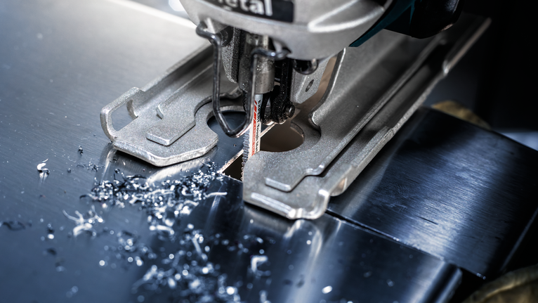 จิ๊กซอว์กำลังเจาะรูที่แม่นยำผ่านแผ่นโลหะมันวาว.