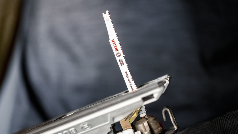 ภาพระยะใกล้ของใบเลื่อยจิ๊กซอว์ที่ติดอยู่กับเครื่องมือไฟฟ้า.