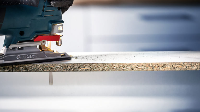 บุคคลที่สวมอุปกรณ์ความปลอดภัยใช้จิ๊กซอว์ตัดแผ่นไม้ลามิเนต.