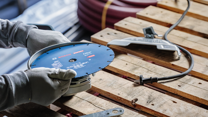 บุคคลที่สวมอุปกรณ์ความปลอดภัยกำลังปรับเครื่องมือไฟฟ้าบนพาเลทไม้