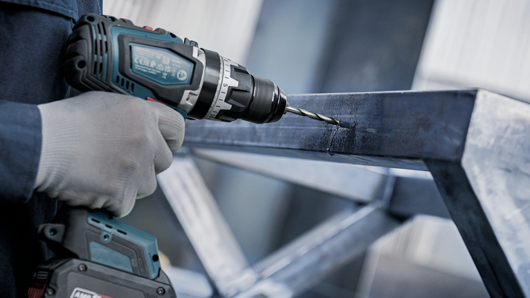 บุคคลที่สวมอุปกรณ์ความปลอดภัยกำลังเจาะเข้าไปในกรอบโลหะ