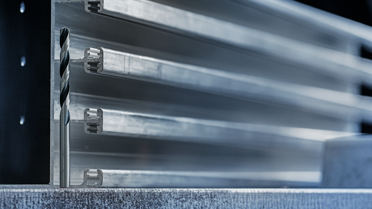 ดอกสว่านวางตั้งตรงบนพื้นผิวโลหะด้านหน้าของโปรไฟล์โลหะที่ซ้อนกัน