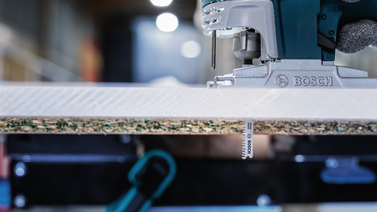 ภาพเลื่อยจิ๊กซอว์กำลังตัดแผ่นไม้ลามิเนตในโรงงาน